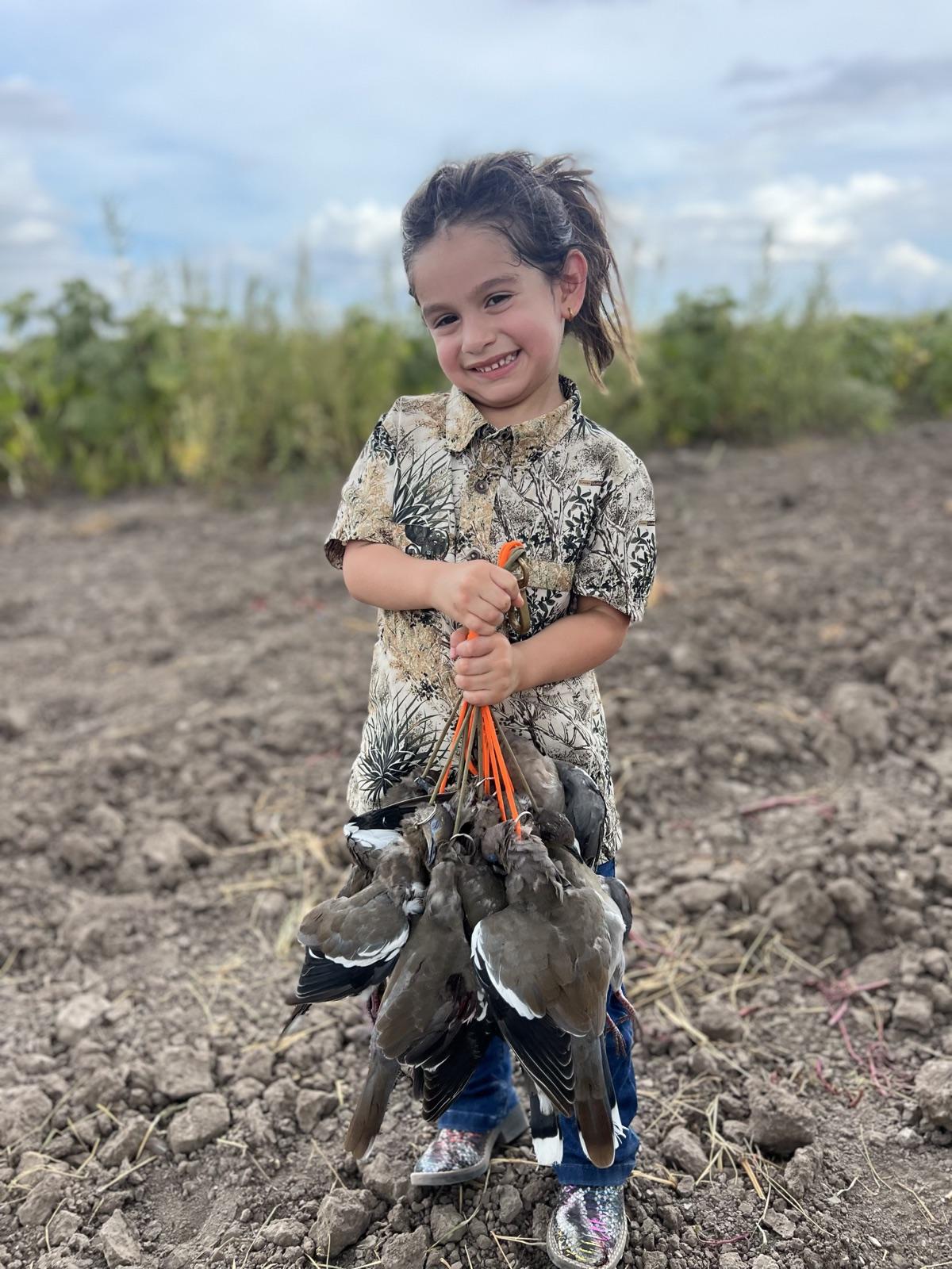 First-time young hunter with her strap of dove on a Valley field