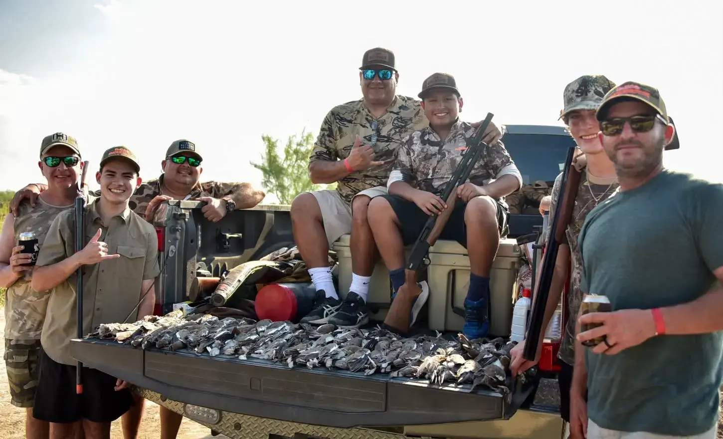 Hunters gathered around a truck tailgate covered with the day's doves