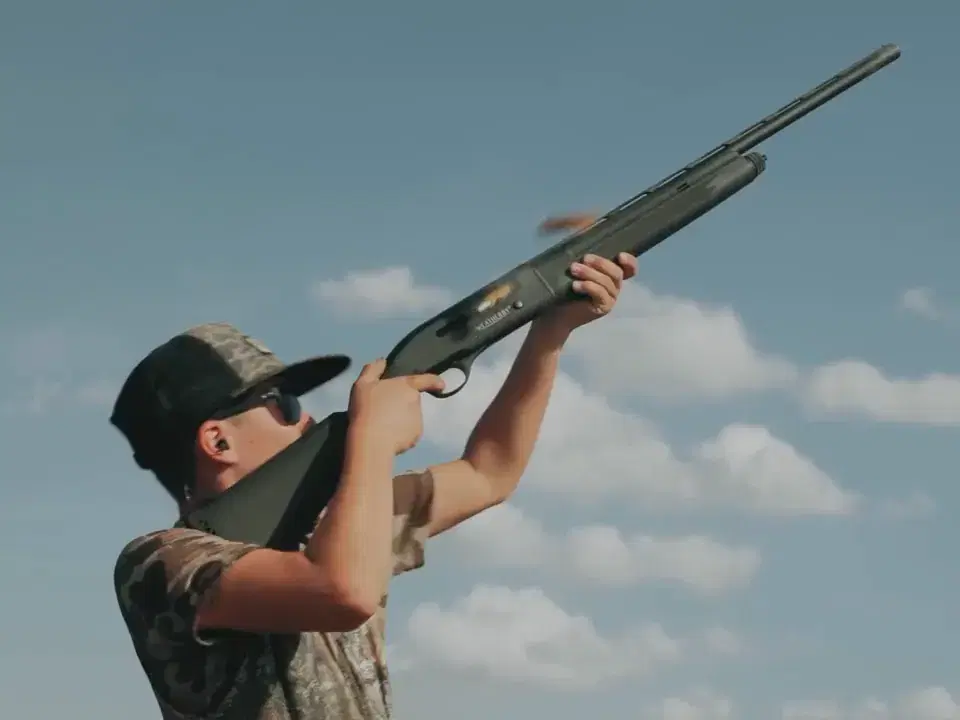 Young hunter aiming a shotgun at the sky