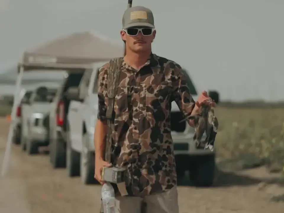 Hunters laughing together in the field and holding up harvested doves
